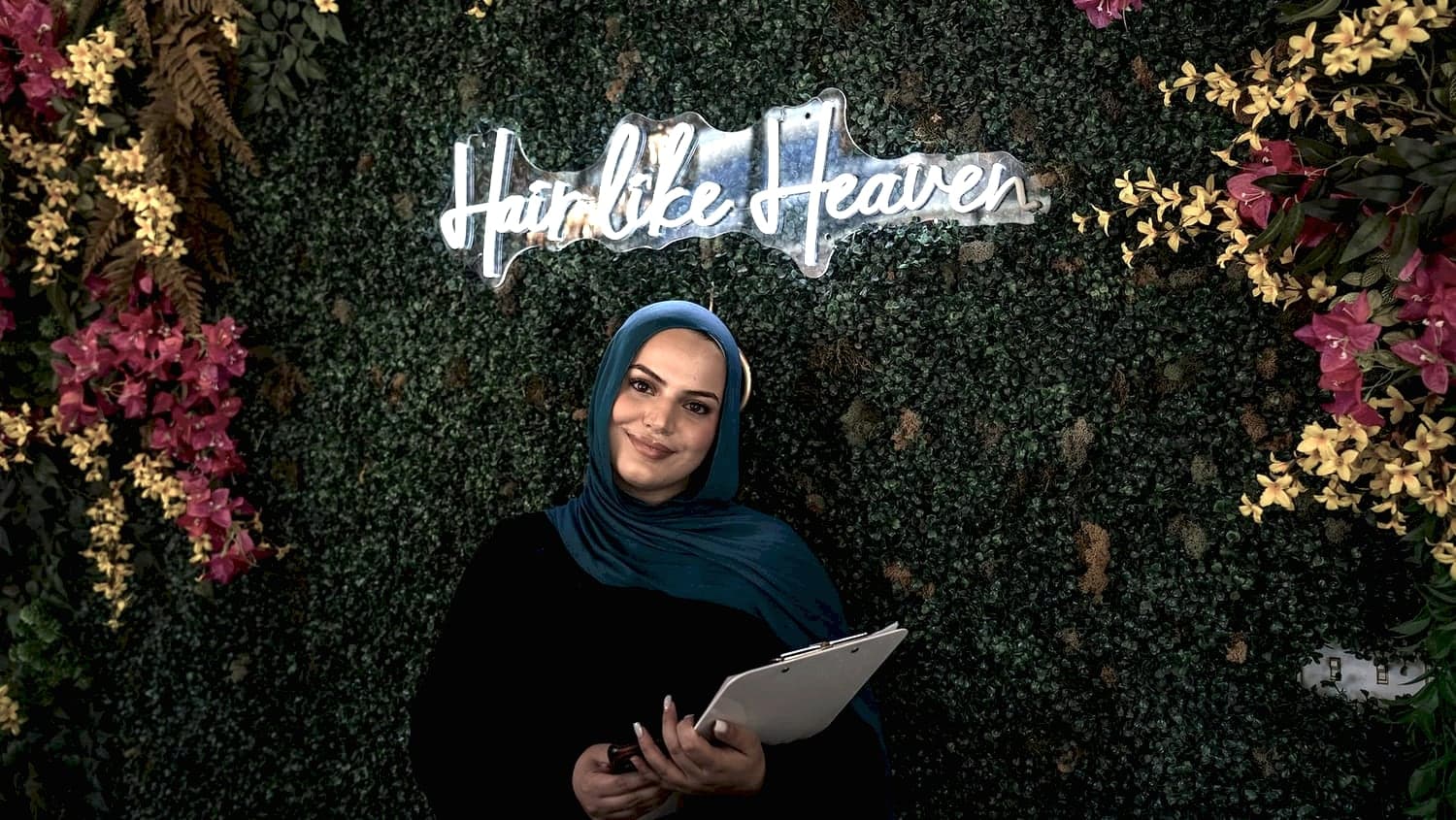 Danyia at the front desk in front of the 'Hair like Heaven' neon wall