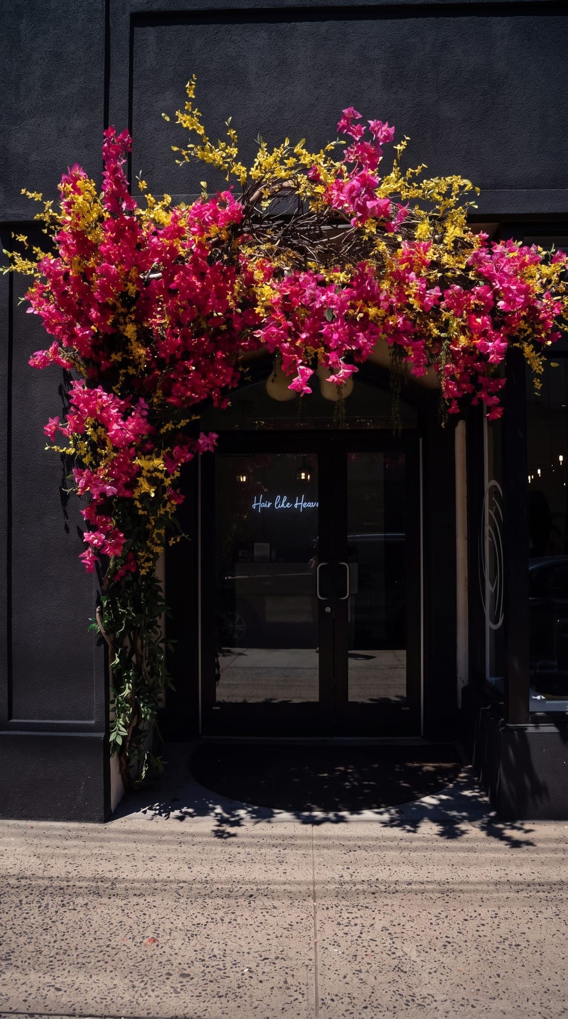 House of Excellence 201's black storefront framed by pink bougainvillea in Bogota, NJ