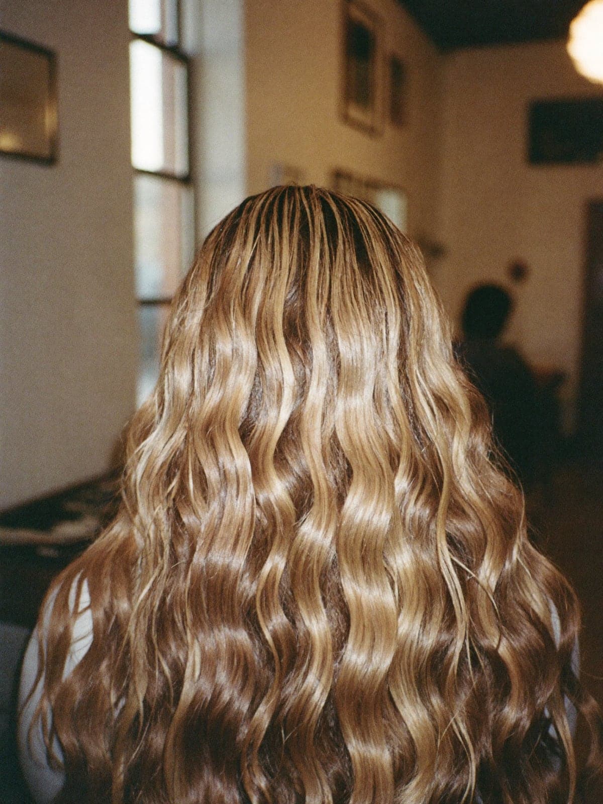 A lived-in bronde balayage melting from blonde through soft brown on beachy waves